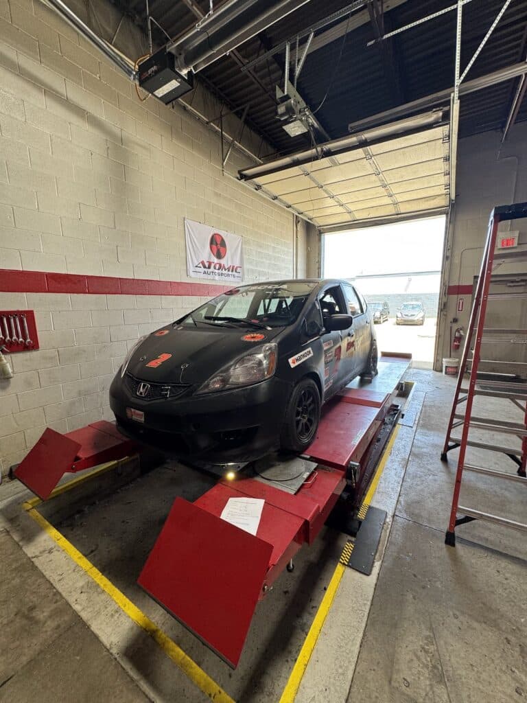 2012 Honda Fit on the lift for suspension work and track inspection at Atomic Autosports.