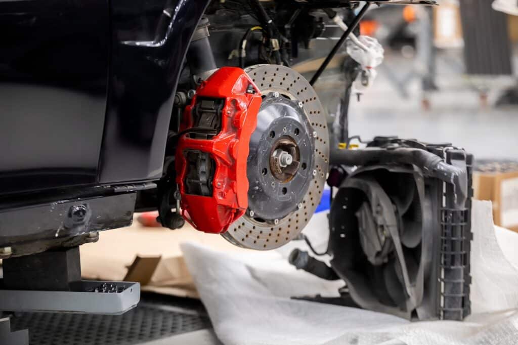 Front disc brake system on race car in process of damaged tyre replacement. The rim is removed showing the front rotor and caliper.