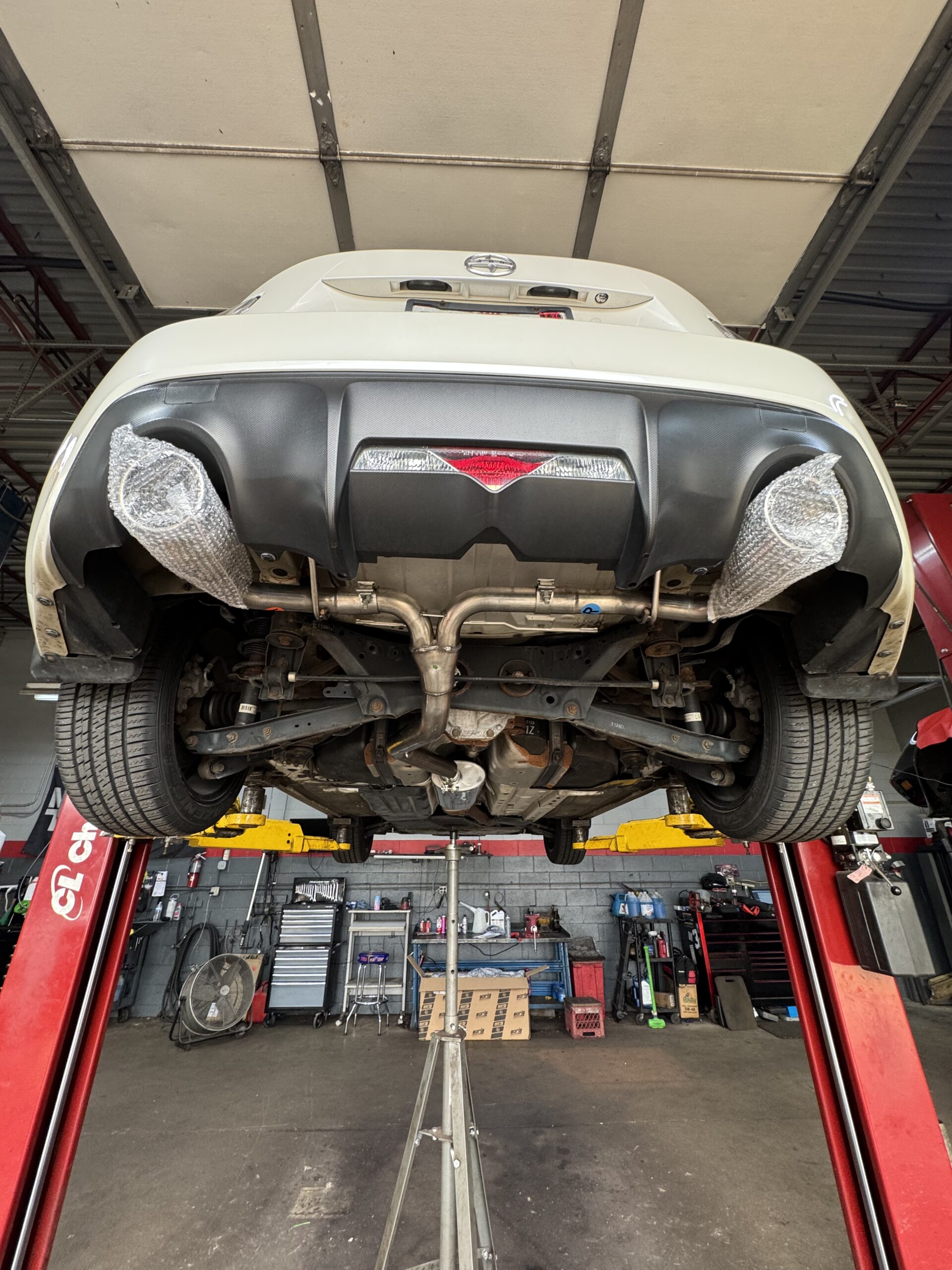 Rear underside of a 2013 Scion FR-S on the lift after Borla cat-back exhaust installation